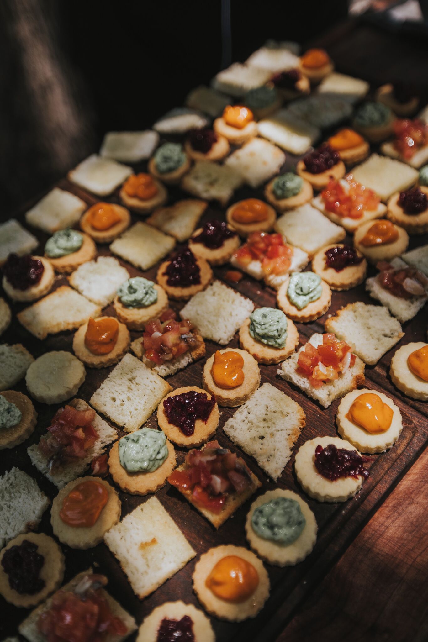 Une variété de petits sandwichs et de hors-d'œuvre disposés sur une table en bois.