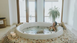 Zona de spa con hidromasaje, suelo de baldosas y un amplio ventanal con vistas al exterior.