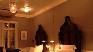 A traditional bedroom with a large bed, a wooden headboard, and a small bedside table with a lamp. - The Eugenia Hotel & Spa (Bangkok)