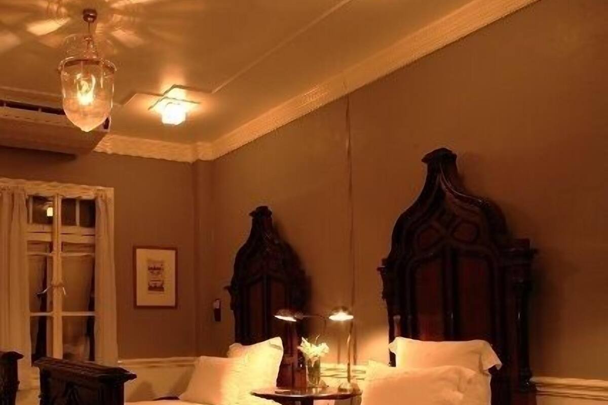 Une chambre à coucher de style traditionnel, avec un grand lit, une tête de lit en bois et une petite table de chevet avec une lampe.