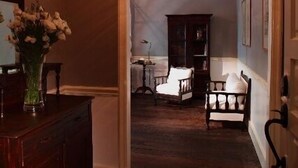 A room with a wooden floor, a desk with a vase of flowers, a chair, and a cabinet. - The Eugenia Hotel & Spa (Bangkok)
