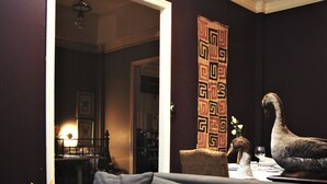A modern living room with a gray sofa, a wooden coffee table with a candle, and a decorative wall piece. - The Eugenia Hotel & Spa (Bangkok)