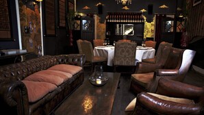 A cozy, vintage-style dining area with leather furniture, a chandelier, and a wine rack. - The Eugenia Hotel & Spa (Bangkok)