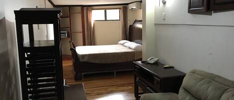 Una habitación de hotel pequeña con cama, escritorio, silla y sofá.