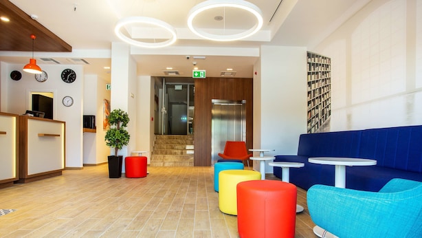 A modern lobby with a reception desk, seating area, and a staircase leading to an elevator. - Best Western Terminus Hotel (Sofia)
