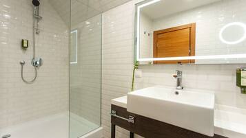 A modern bathroom with a glass-enclosed shower, a white sink with a wooden cabinet above, and a mirror with a wooden frame.