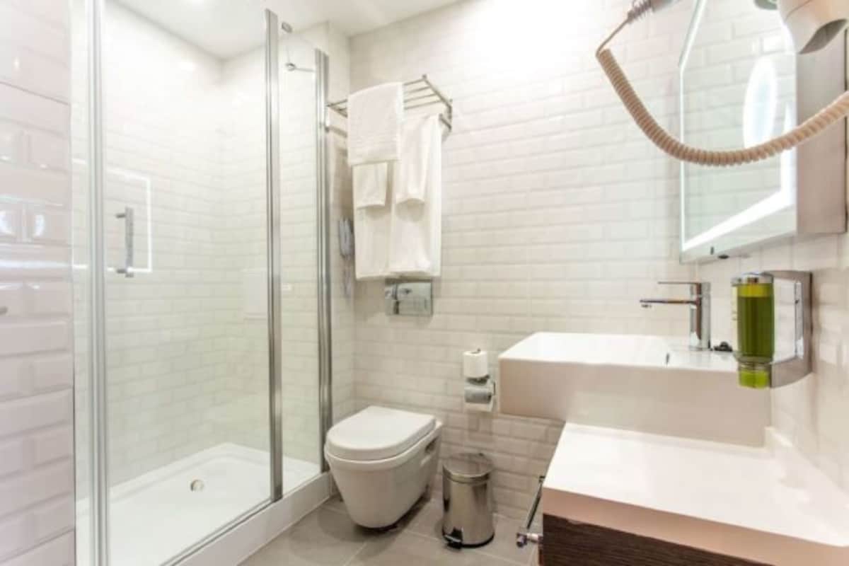 A modern bathroom with a glass shower enclosure, a toilet, a sink, and a towel rack.