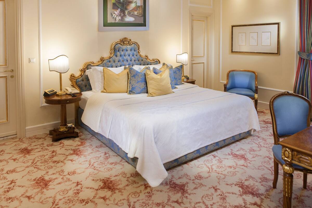 A hotel room with a large bed, two bedside tables, a chair, and a small table.