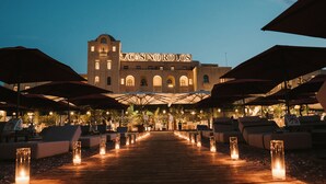 A building with a sign reading "CASINO RODOS" at the entrance, surrounded by outdoor seating with umbrellas and candles on the pathway. - Grande Albergo delle Rose (Rhodes)