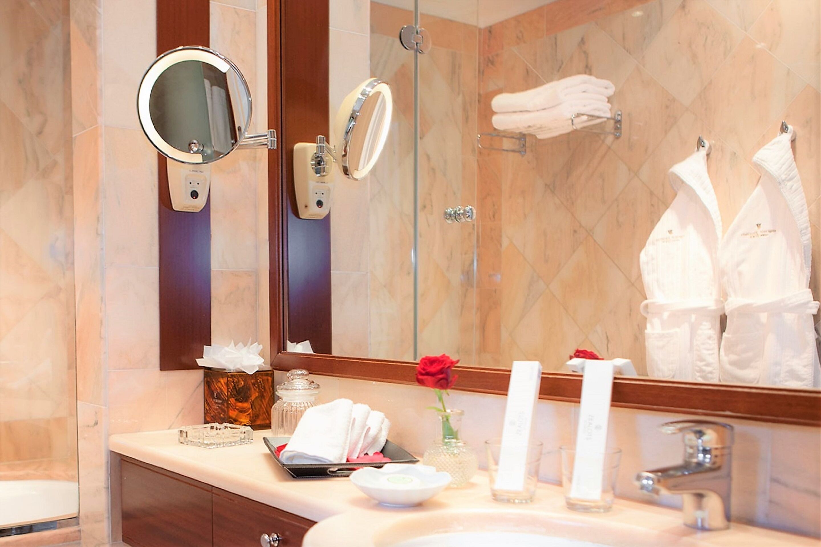 Un baño con un espejo grande, cabina de ducha de vidrio y tocador con artículos de aseo.