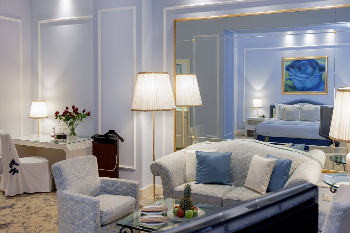 A hotel room with a bed, a sofa, a desk, and a TV.