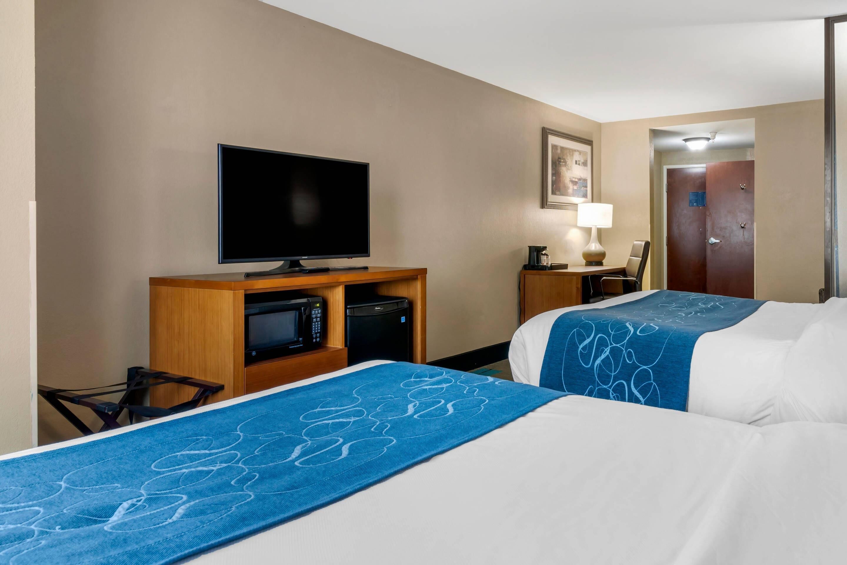 A hotel room with two beds, a television, a microwave, and a coffee maker.