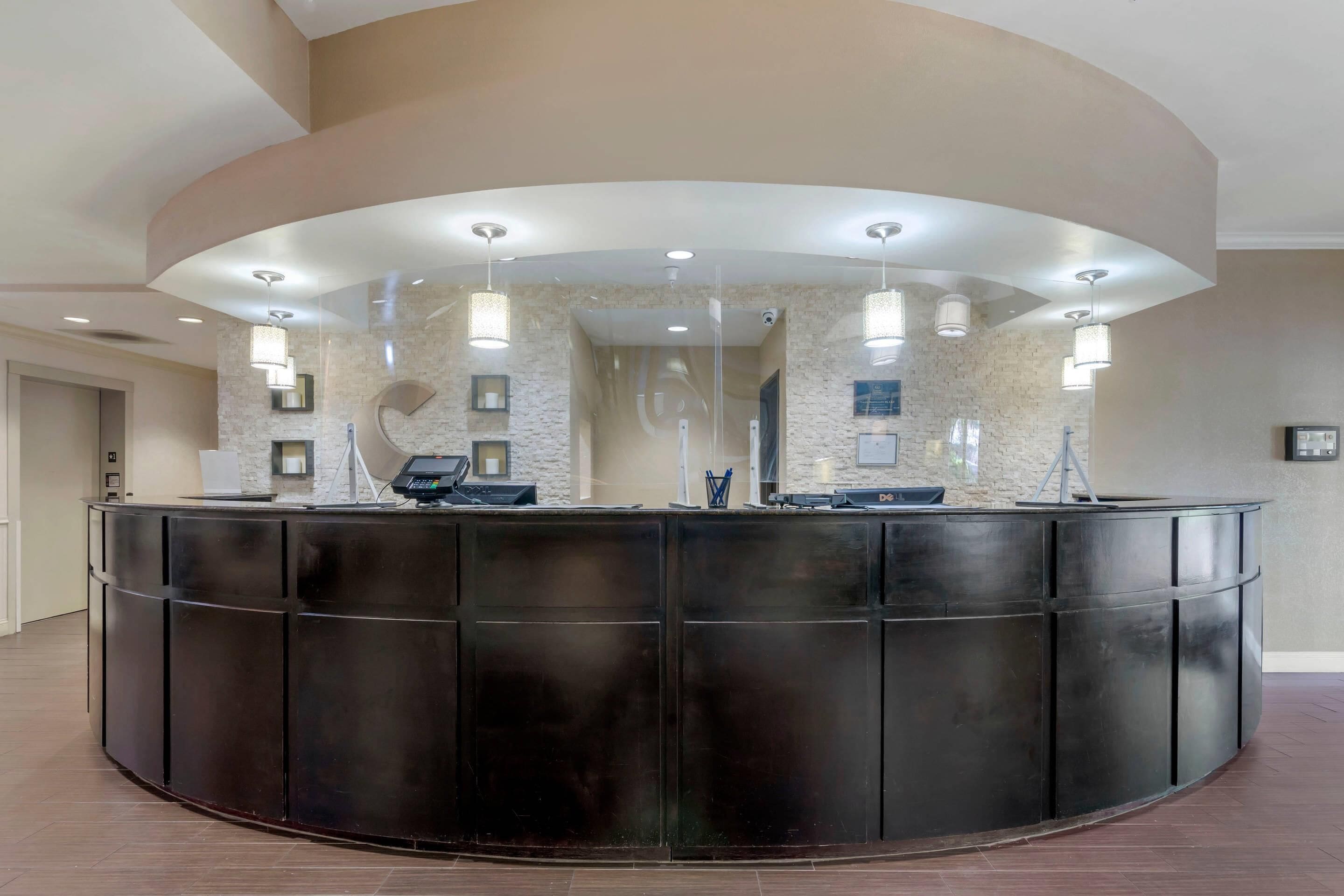 A reception desk with a curved design, multiple light fixtures, and a stone wall backdrop.