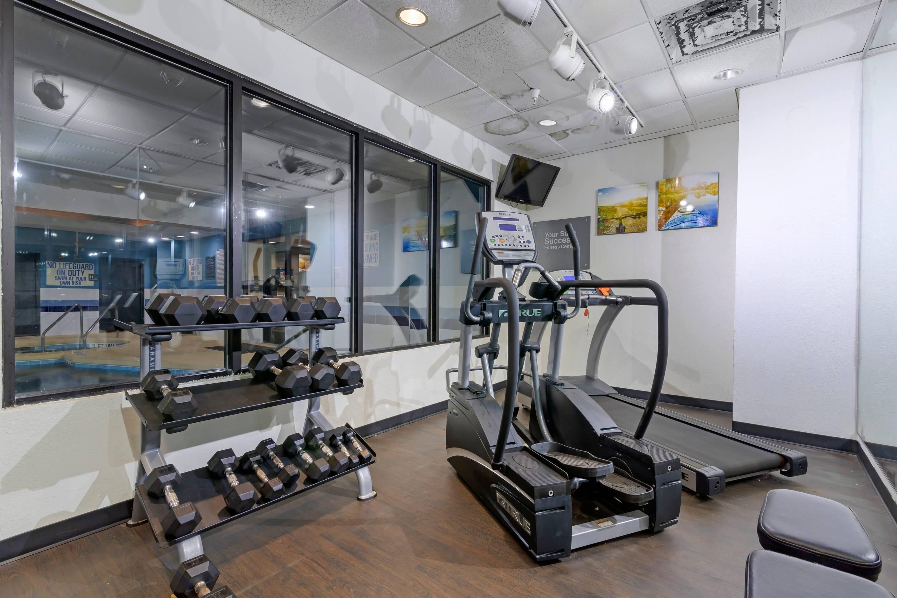 Un gimnasio con equipo de ejercicio, una cinta de correr y un espejo grande.