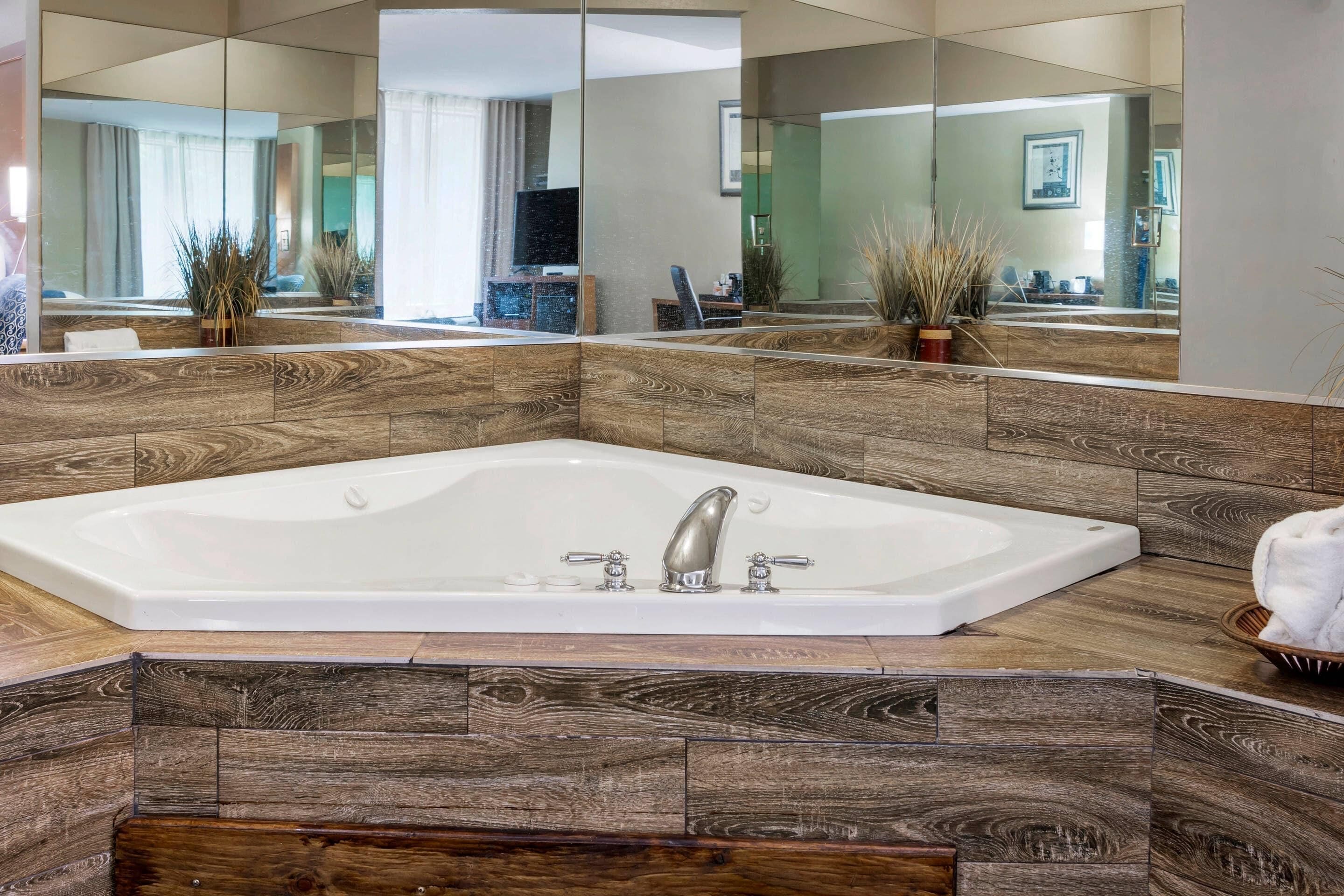 Une salle de bain moderne avec une grande baignoire sur pieds, des panneaux muraux en bois et un grand miroir qui reflète la pièce.