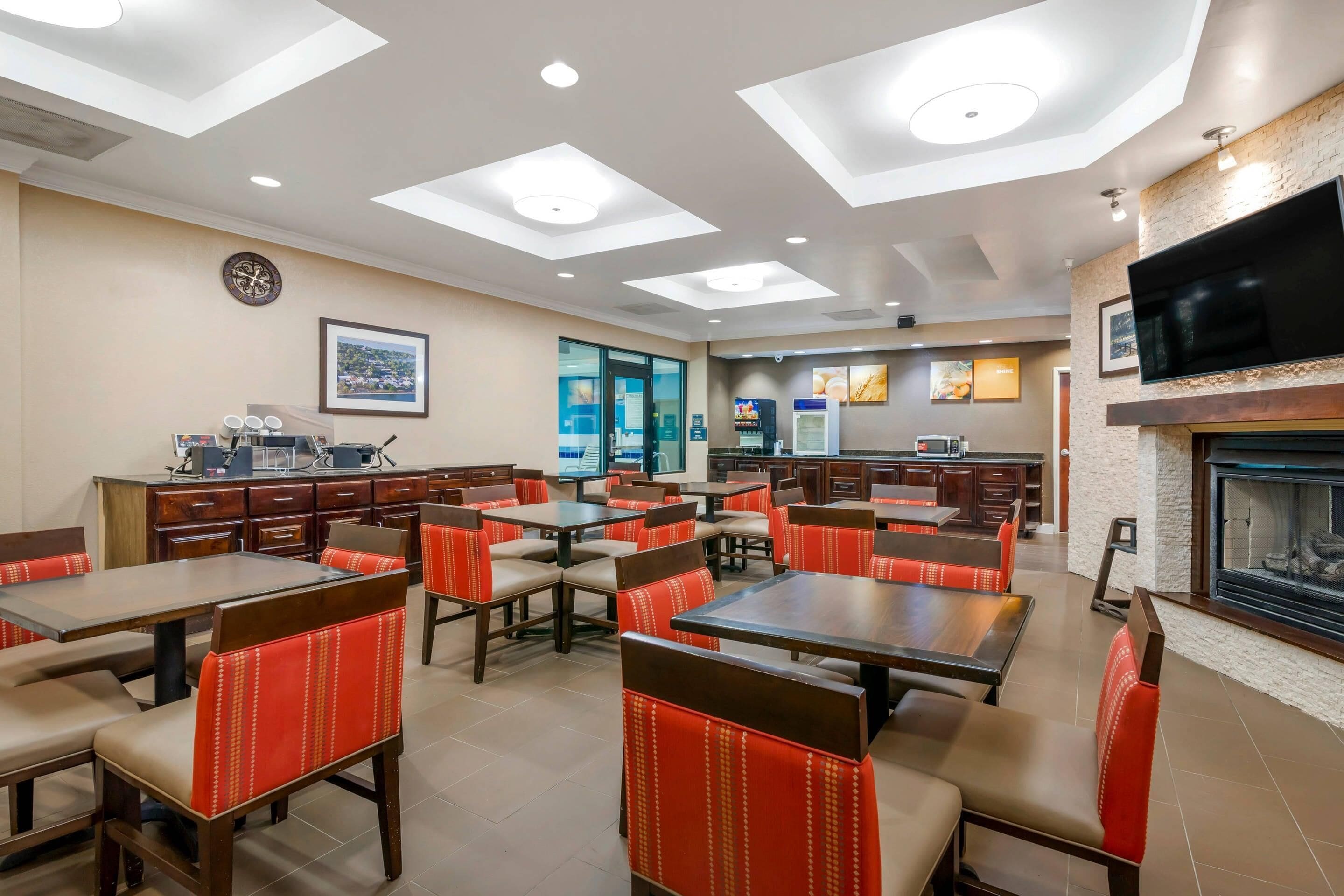 A restaurant with multiple tables and booths, a kitchen area, and a fireplace.
