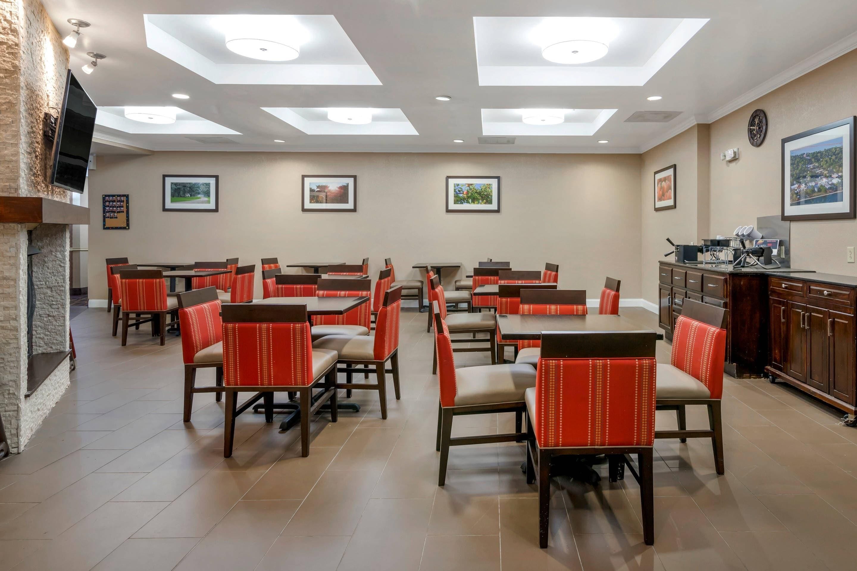 A dining area with multiple tables and chairs, a fireplace, and artwork on the walls.
