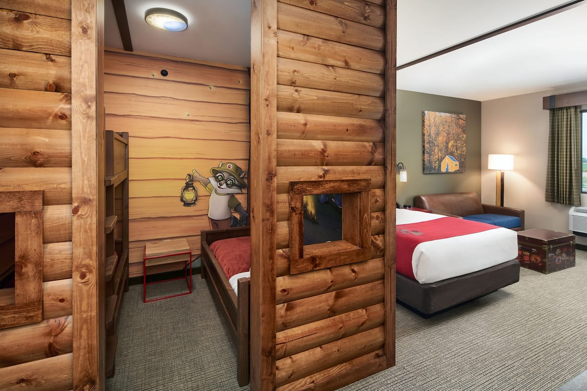 Ein rustikal eingerichtetes Blockhauszimmer mit einem Bett, einem Schreibtisch und einem Stuhl.