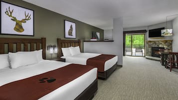 A hotel room with two beds, a fireplace, a TV, and a balcony with outdoor seating.