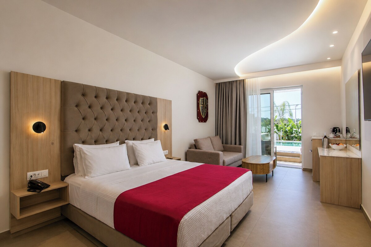 Una habitación de hotel moderna con una cama grande, un escritorio, una silla y vistas al exterior.