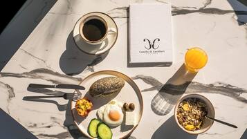 En frukostuppsättning på ett marmorbord med en kopp kaffe, en tallrik med ägg, rostat bröd och en skål med flingor.
