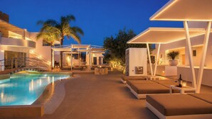 Un espace aménagé au bord de la piscine, avec des chaises longues, une piscine et un escalier menant à un niveau supérieur.