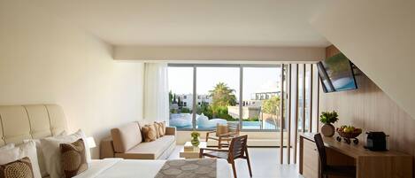 A modern hotel room with a large bed, a sofa, a dining area, and a view of a swimming pool.