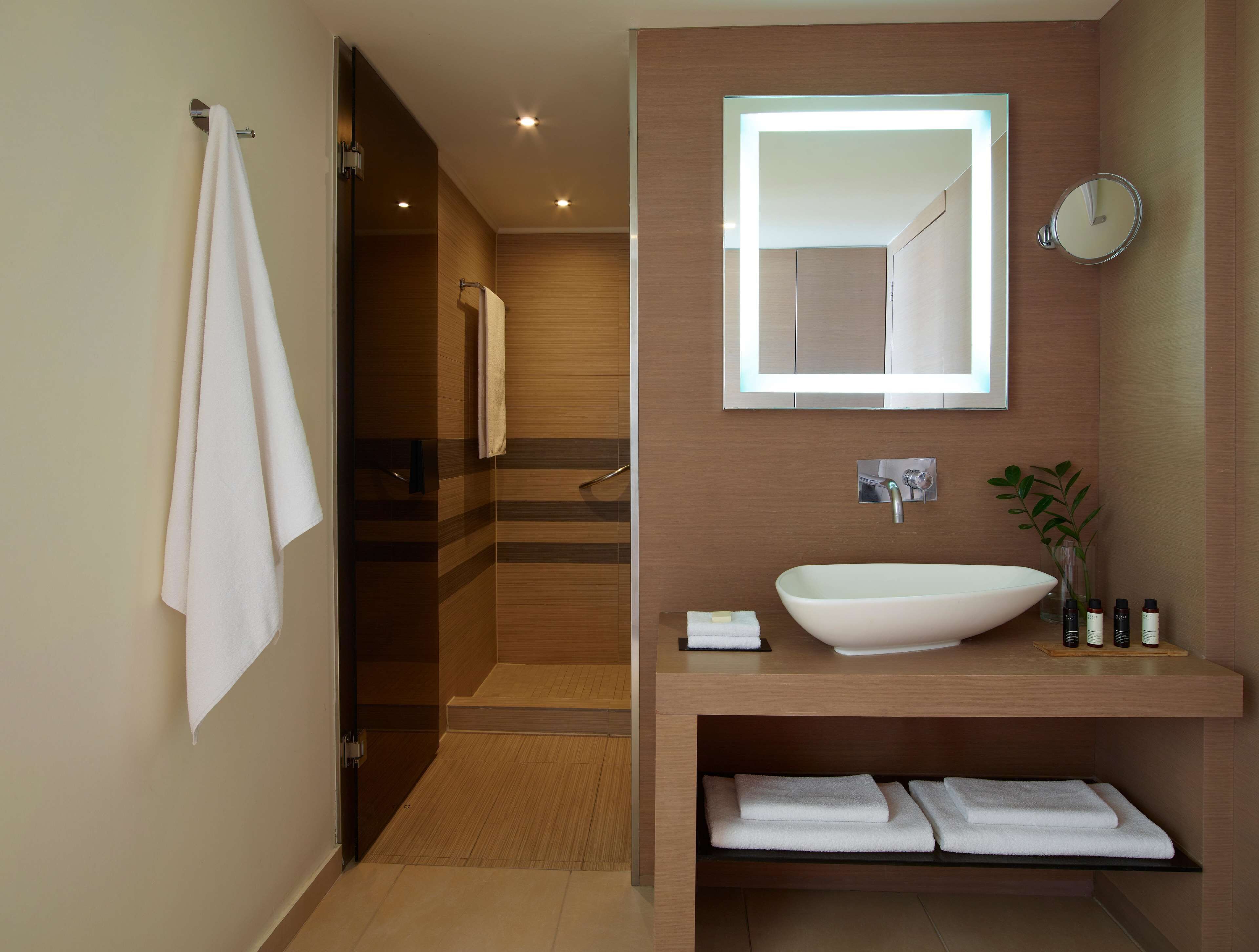 Un baño moderno con un espejo grande, un lavabo sobre encimera y una ducha a pie.