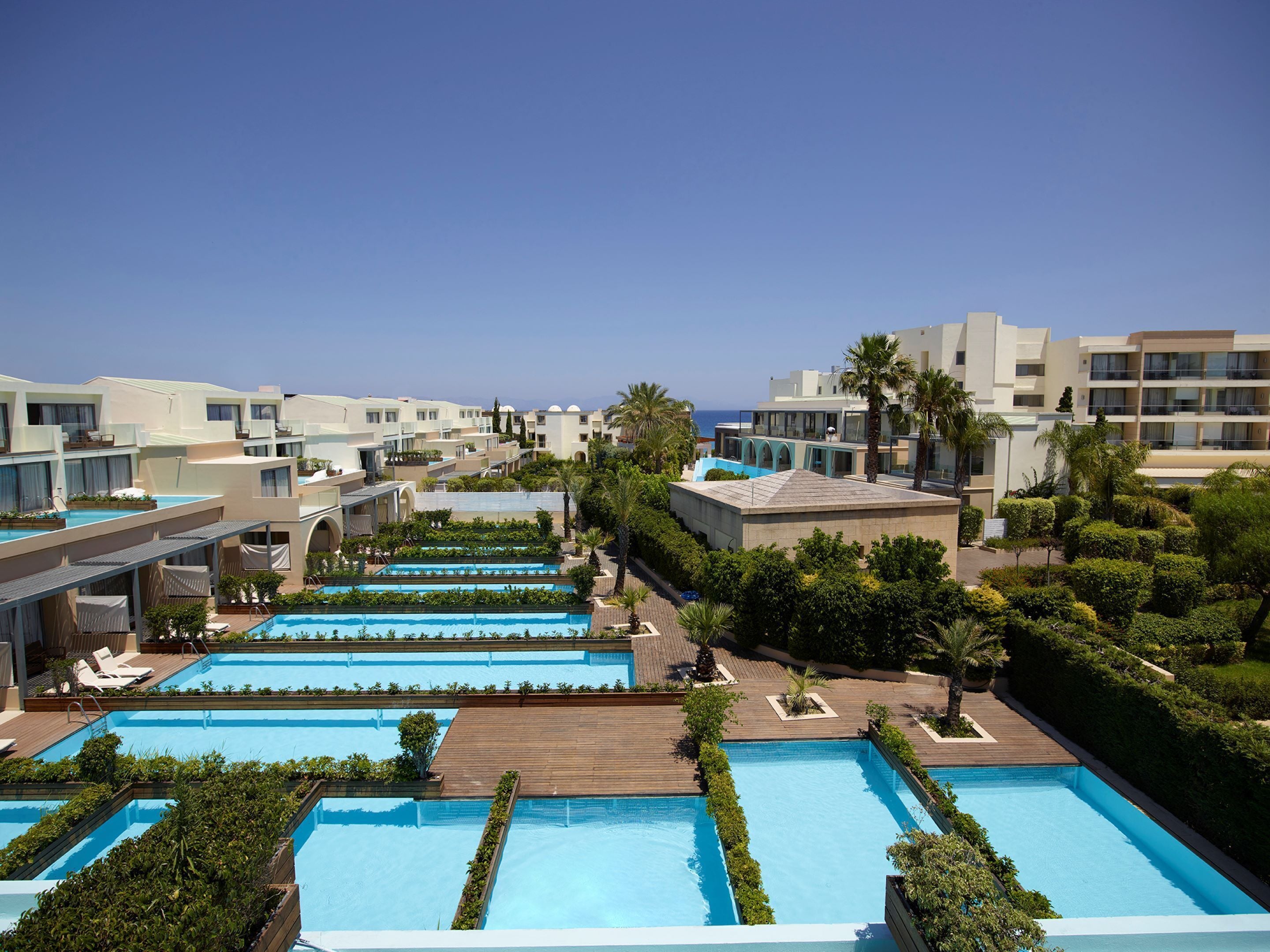 Un resort con varias piscinas, palmeras y edificios modernos.