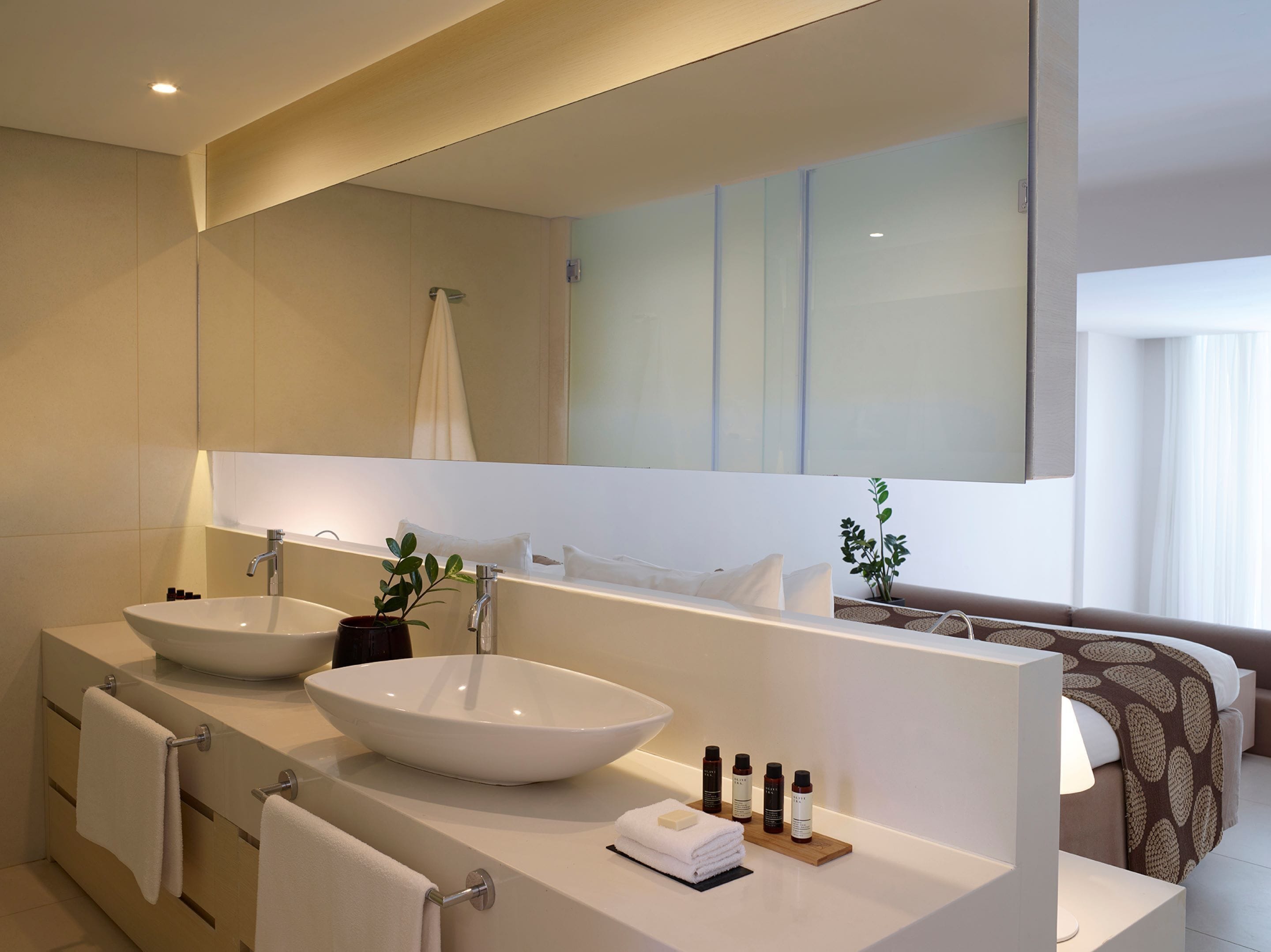 Een moderne badkamer met twee wasbakken, een grote spiegel en een bad.