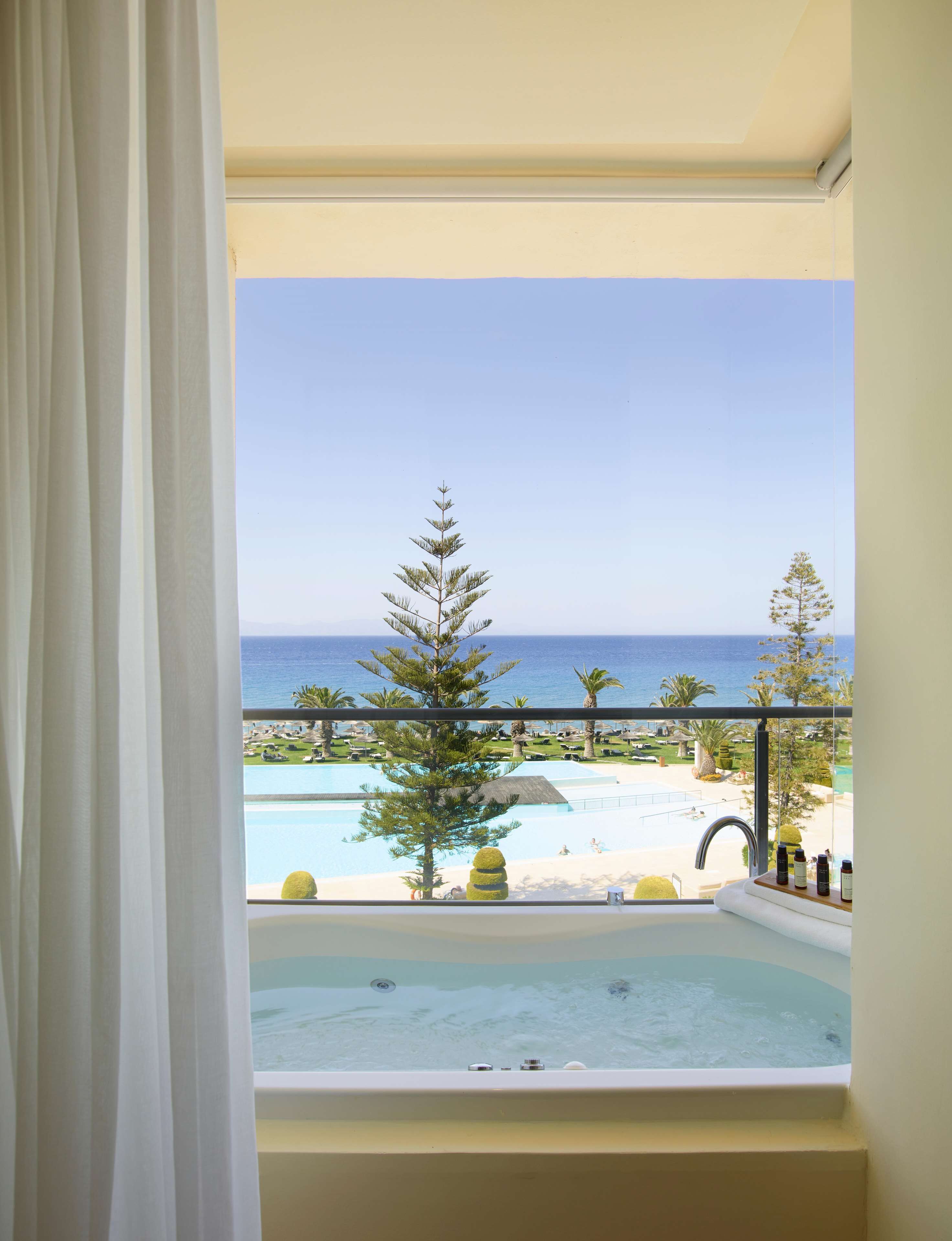A balcony with a view of a pool and the sea.