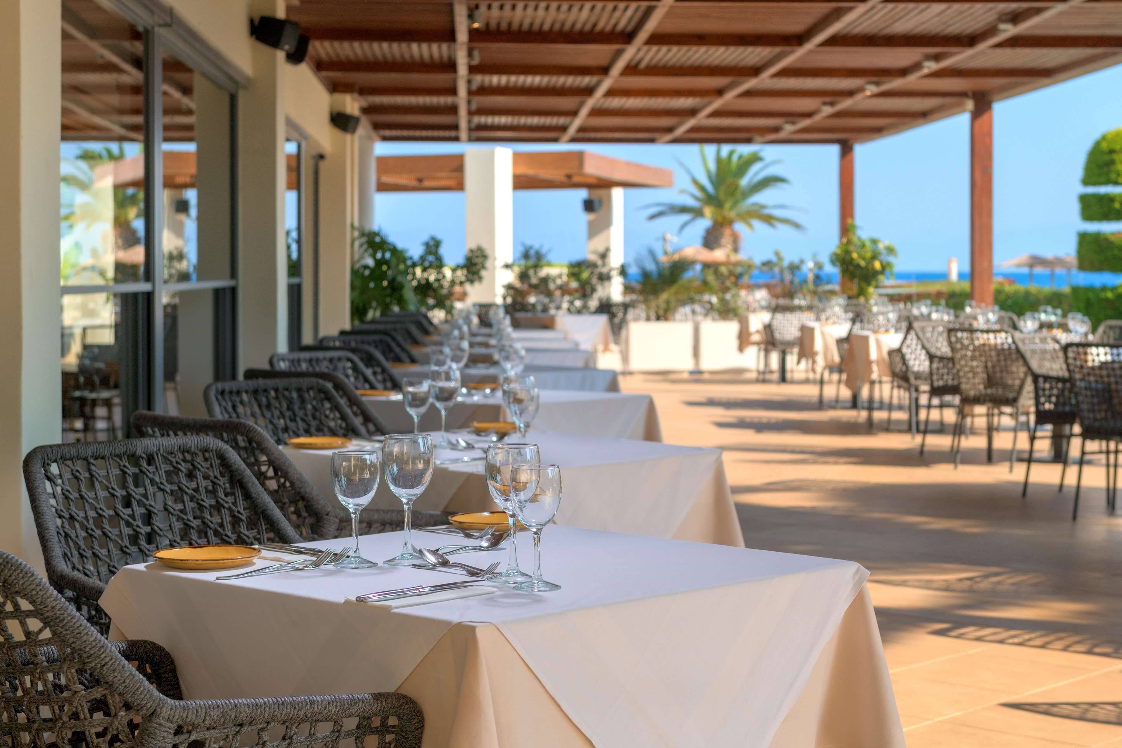 Bord- og stolearrangement på en udendørs terrasse med udsigt over havet.