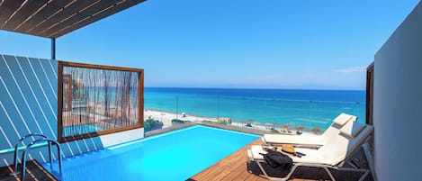 A poolside area with a view of the sea, a wooden deck, and lounge chairs.