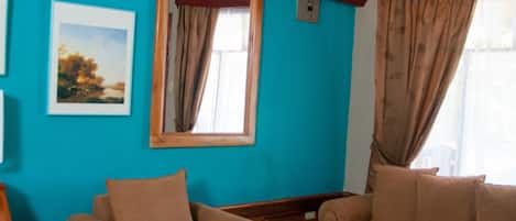 Una sala de estar con dos sofás color beige, una mesa de centro de madera y un ventanal con cortinas.
