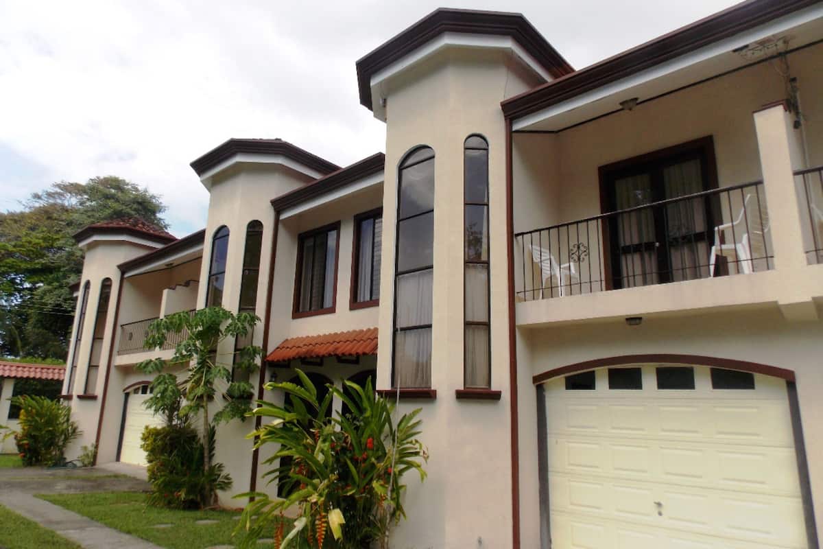 A two-story residential building with a white facade, multiple windows, and a garage.