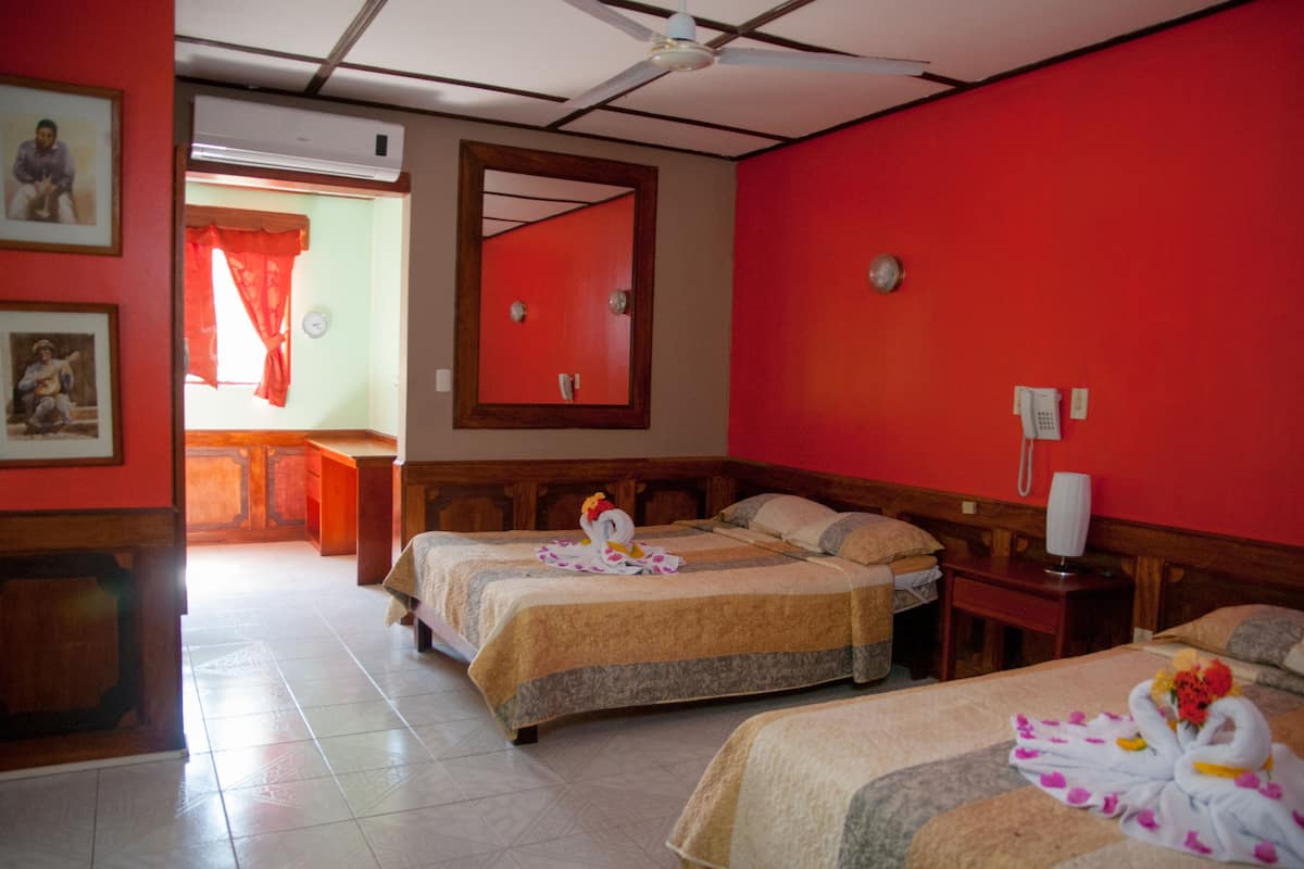 A hotel room with two beds, a wooden headboard, a mirror, a telephone, and a red wall.