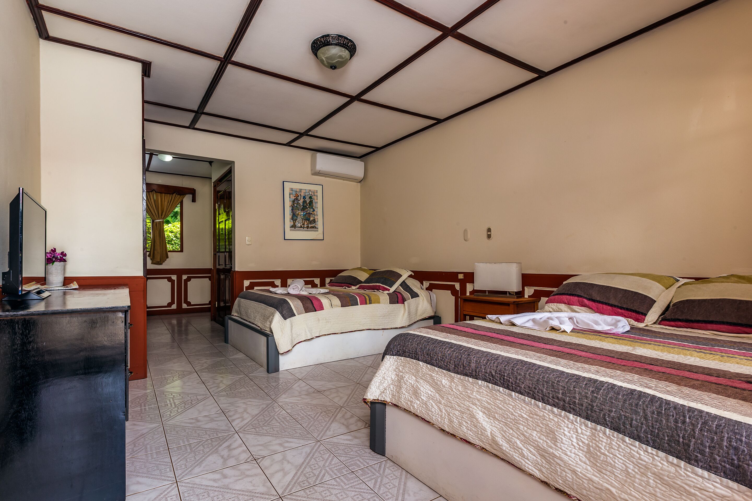 Ein Hotelzimmer mit zwei Betten, einem Schreibtisch und einem Fernseher.