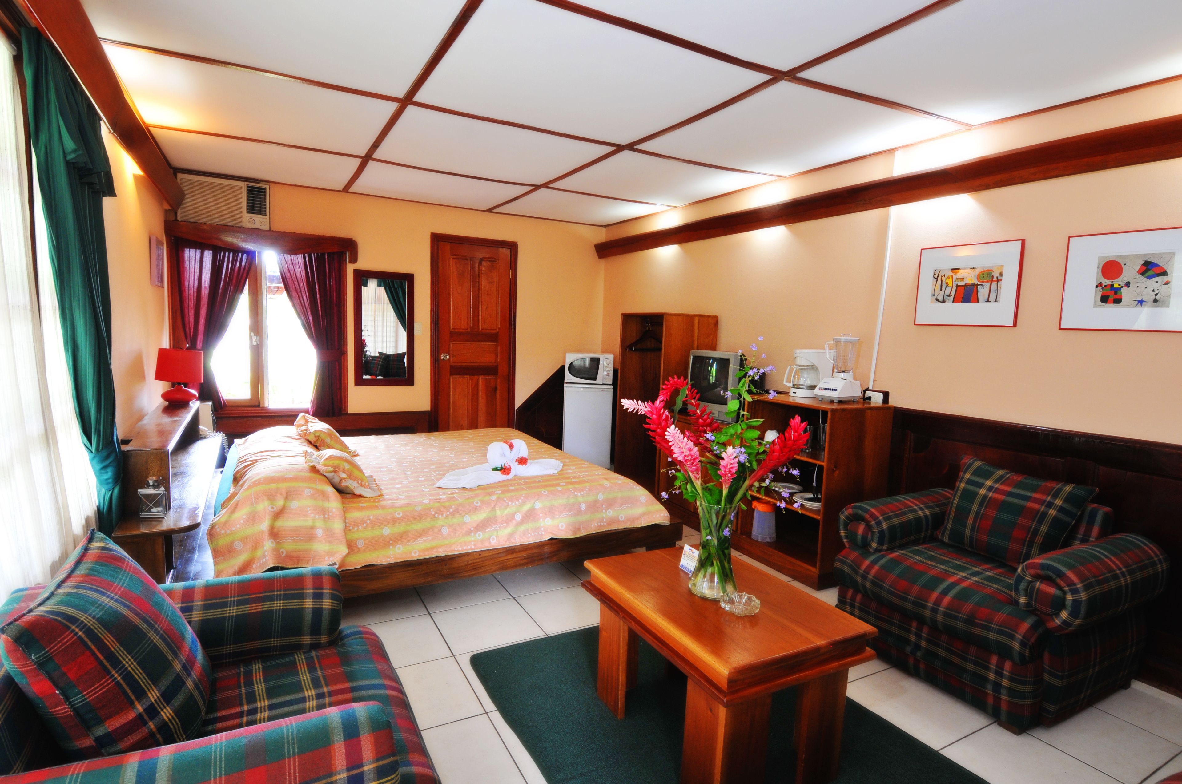 Quarto de hotel com uma cama, dois sofás, uma mesa, uma TV e um micro-ondas.