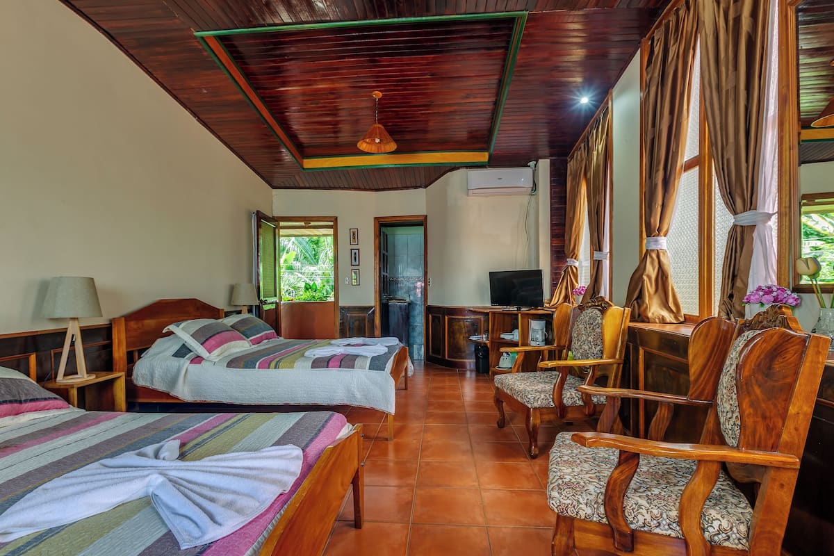 A hotel room with two beds, a desk, a chair, and a television.