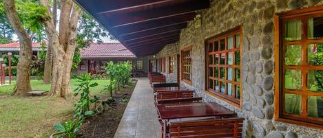 A covered outdoor seating area with stone walls and wooden benches.