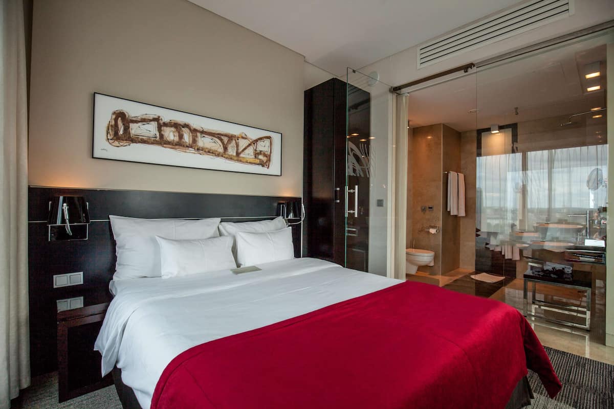 Una habitación de hotel con una cama grande, cabina de ducha de vidrio y un baño moderno.
