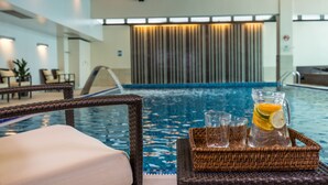 Zona junto a la piscina con una silla de mimbre, una bandeja con vasos y una jarra de agua, y vistas a la piscina.