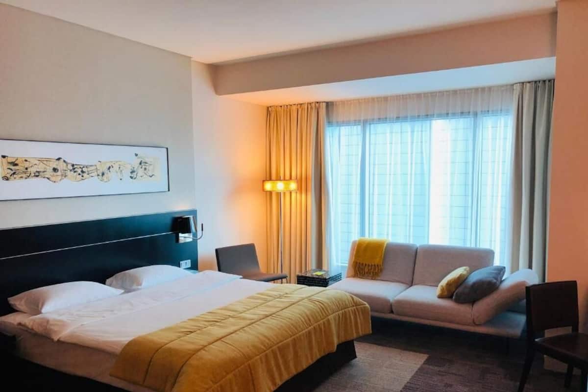 Una habitación de hotel con cama, sofá, escritorio y lámpara.