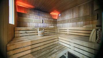 Un sauna avec des bancs en bois et un seau en bois.