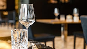 Una mesa de comedor con una copa de vino y un vaso de agua, preparada con servilleta y tenedor.
