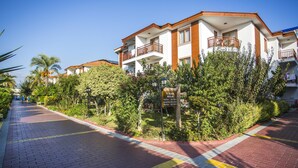 A residential building with balconies, a brick pathway, and surrounding greenery. - Eftalia Village Hotel - All Inclusive (Alanya)