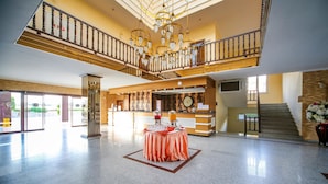 A spacious lobby with a reception desk, a clock, and a staircase leading to an upper level. - Eftalia Village Hotel - All Inclusive (Alanya)