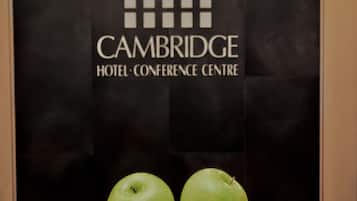 Een poster met de tekst 'CAMBRIDGE HOTEL-CONFERENCE CENTRE' en een schaal groene appels.