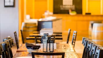 Interior de un restaurante con una mesa de madera preparada para comer, sillas negras con detalles metálicos y faroles negros sobre la mesa.