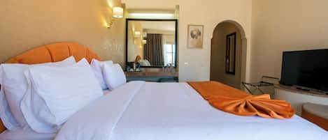 Ein Hotelzimmer mit einem großen Bett, einem Fernseher und einem im Hintergrund sichtbaren Badezimmer.